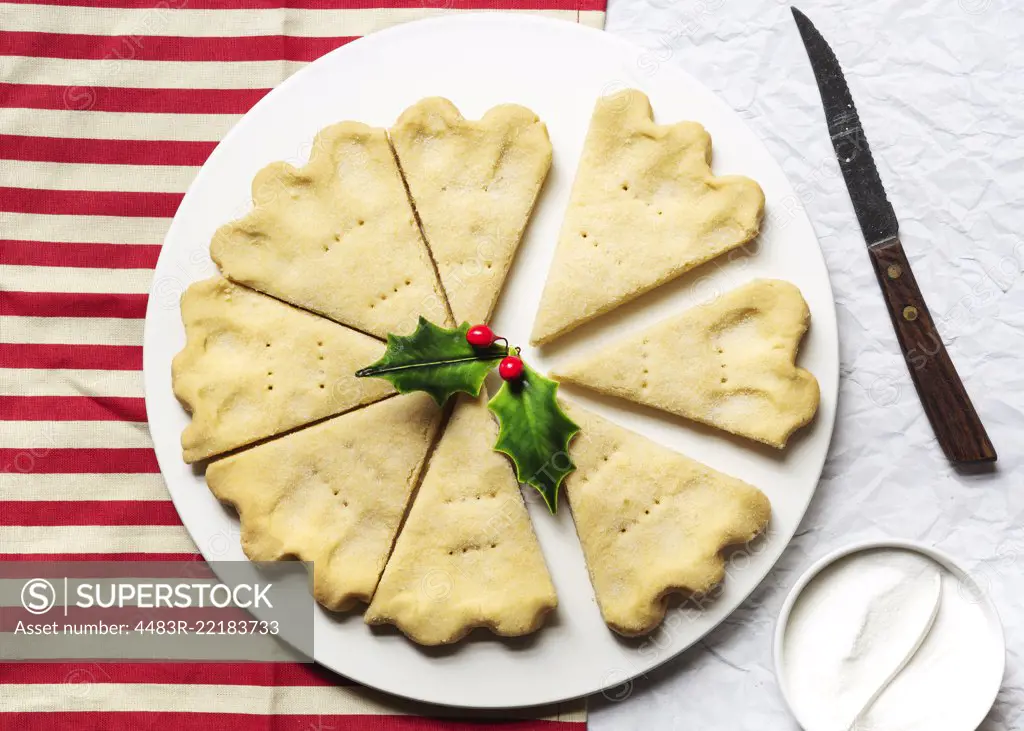 A plate of Scottish shortbread wedges on a red and white striped cloth.