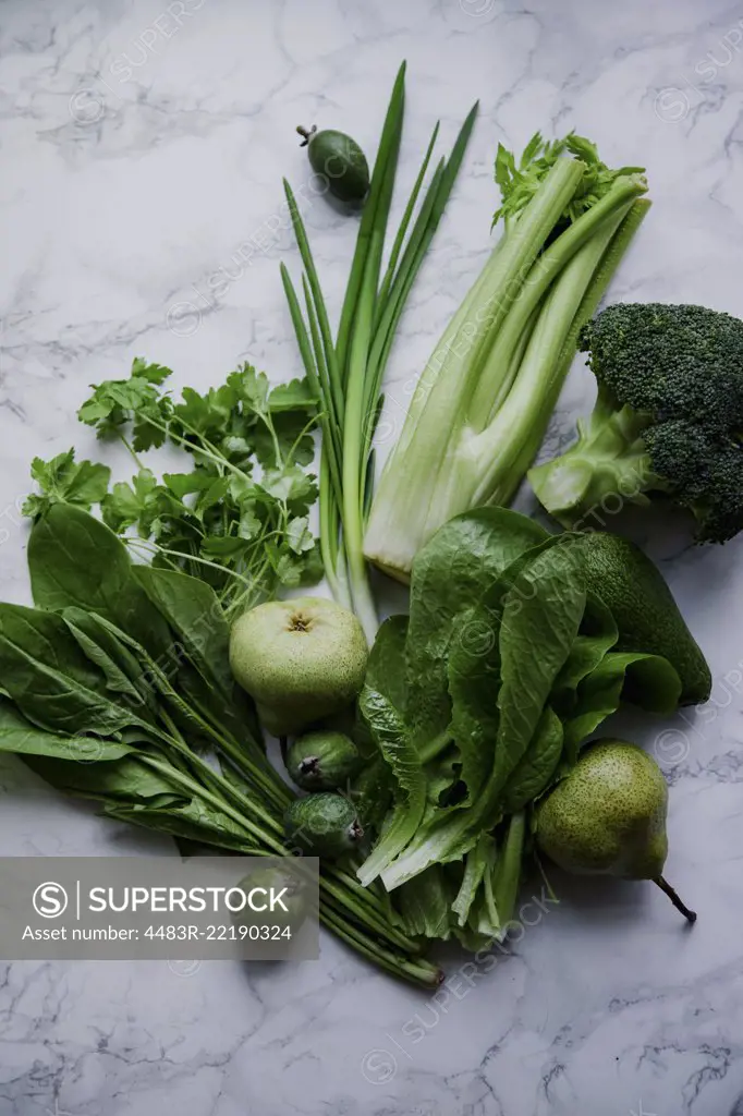 Fresh green food, variety of vegetables, greens and fruits on marble surface. Healthy eating concept. Monochromatic idea.