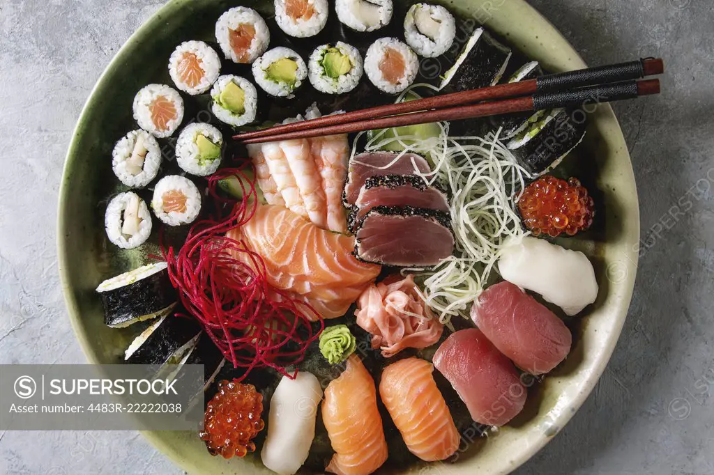 Sushi Set nigiri sashimi and sushi rolls in ceramic serving plate with salad and chopsticks over grey concrete background. Flat lay, space. Japan menu