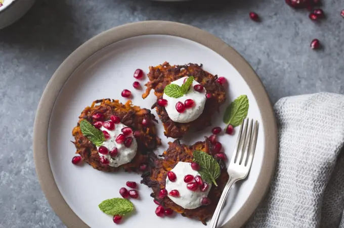 Harissa sweet potato latkes with spiced yogurt, mint and pomegranate, gluten-free.