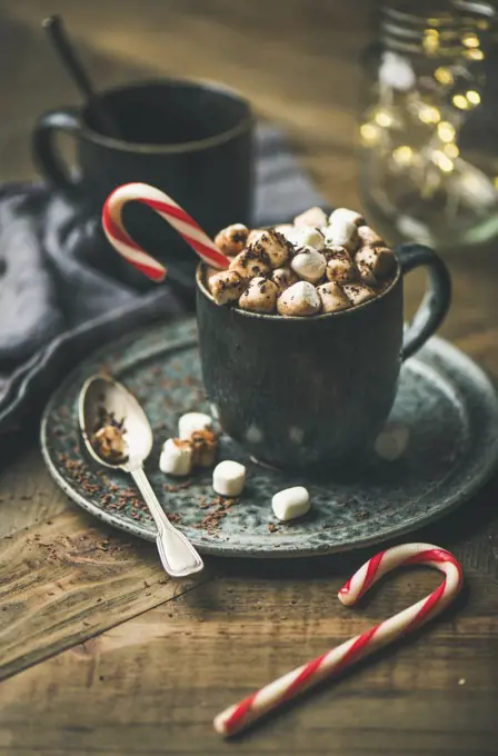 Winter warming sweet drink hot chocolate with marshmallows and cocoa in mug with Christmas holiday candy cane on wooden background, selective focus, copy space