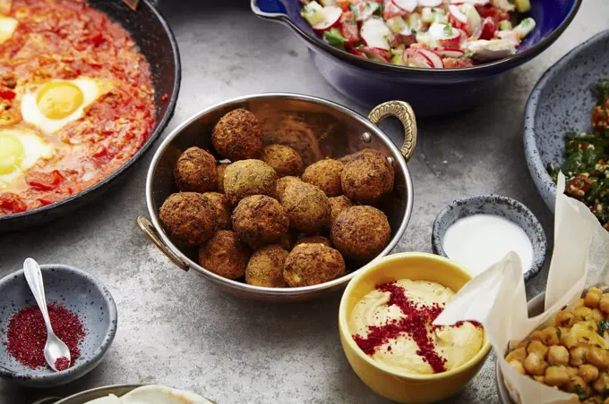 Side view of traditional jewish and middle eastern food: falafel, fattoush, tabouli, shakshuka, balila, hummus and spicy beetroot dip. Israeli cuisine concept