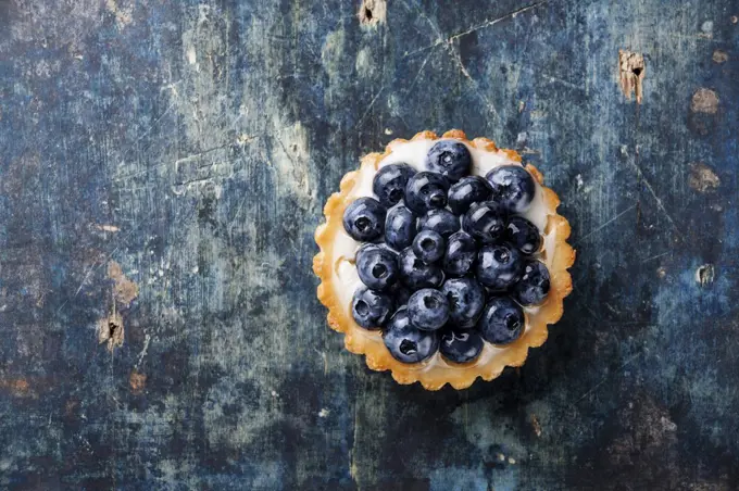 Blueberry tart on blue wooden background