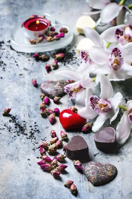 Chocolate candies heart shaped with dry tea roses and orchids for Valentine's Day.