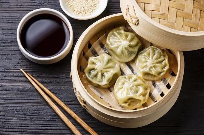 Steamed dumplings Dim Sum in bamboo steamer on black burned wooden background