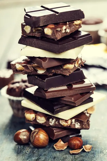 An assortment of white, dark, and milk chocolate with nuts - on wooden board