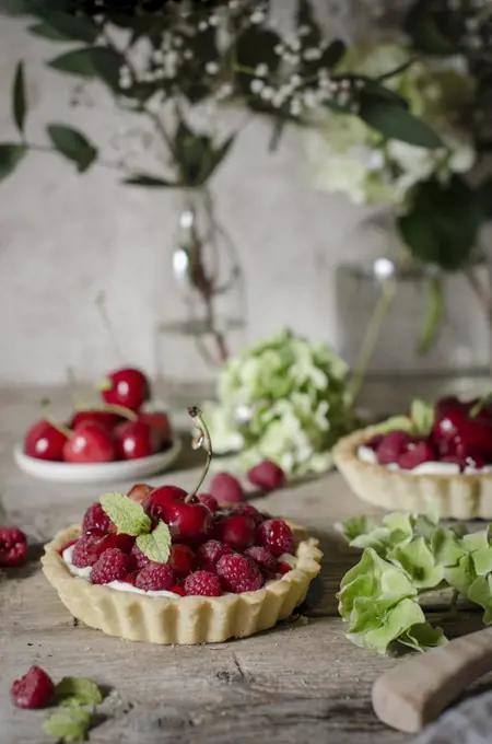 A cherry and raspberry tart on a kitchen table.