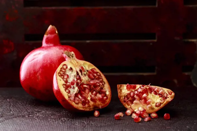 Pomegranate Seeds , some peeled and whole on a dark background