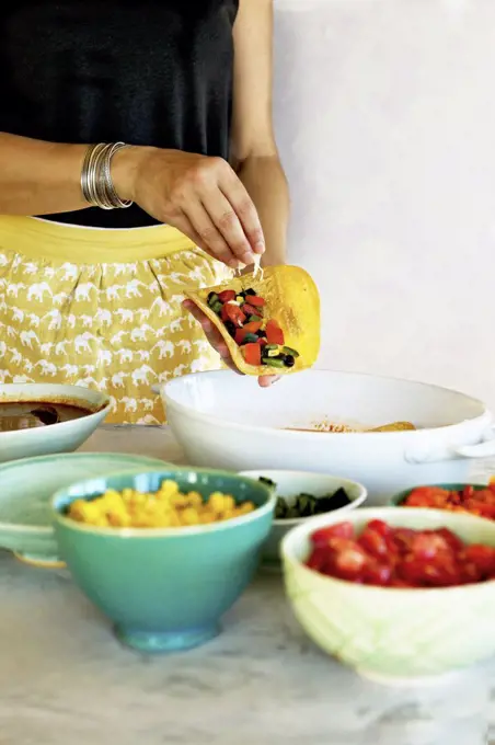 A woman making Black Bean Vegetable Enchiladas with home made enchilada sauce.