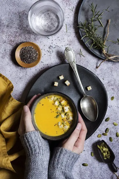 Hands of woman holding a hot pumpkin soup