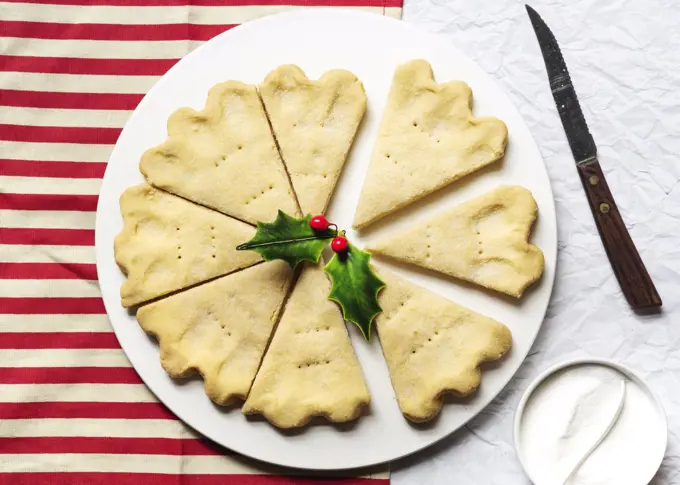 A plate of Scottish shortbread wedges on a red and white striped cloth.