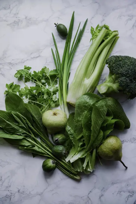 Fresh green food, variety of vegetables, greens and fruits on marble surface. Healthy eating concept. Monochromatic idea.