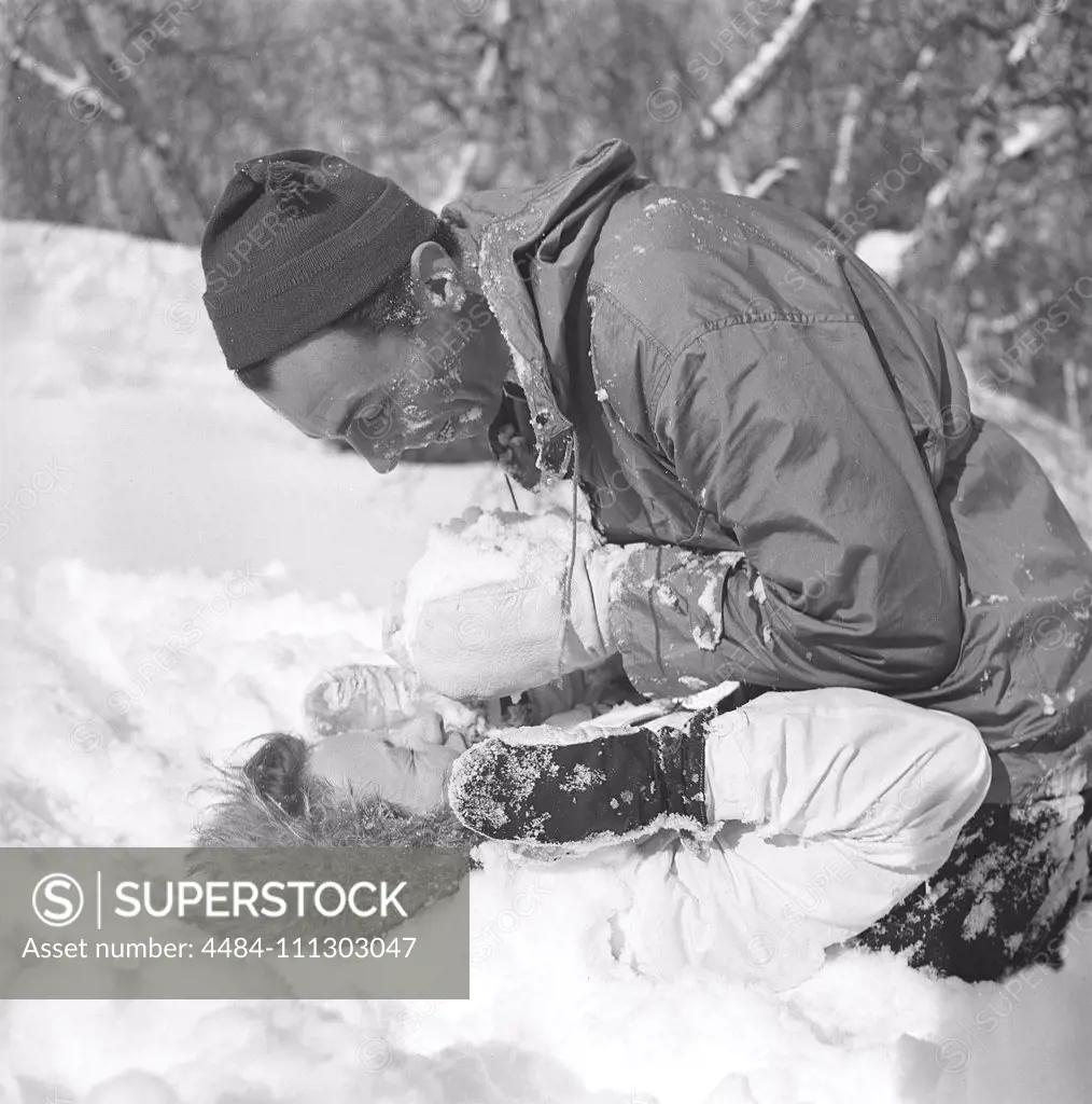 Winter in the 1940s. Actor Nils Kihlberg, 1915-1965 is pictured here with his wife Ann-Britt. They are both wearing winter clothes and plays in the snow laughing. Sweden 1943. Kristoffersson Ref D71-3