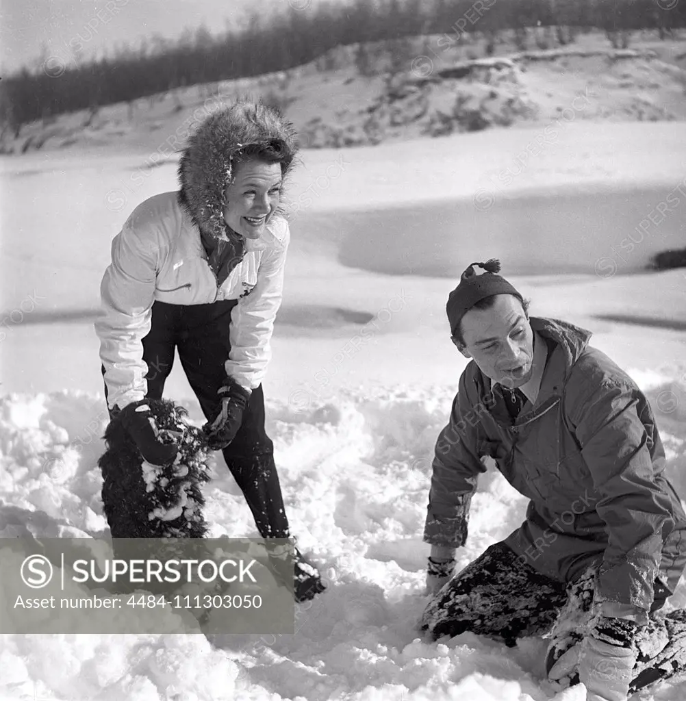 Winter in the 1940s. Actor Nils Kihlberg, 1915-1965 is pictured here with his wife Ann-Britt. They are both wearing winter clothes and plays in the snow laughing. Sweden 1943. Kristoffersson Ref D71-1