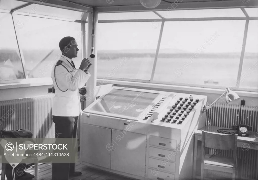 Air traffic controller in the 1940s. An officer in the airport control tower is monitoring the runway with binoculars.