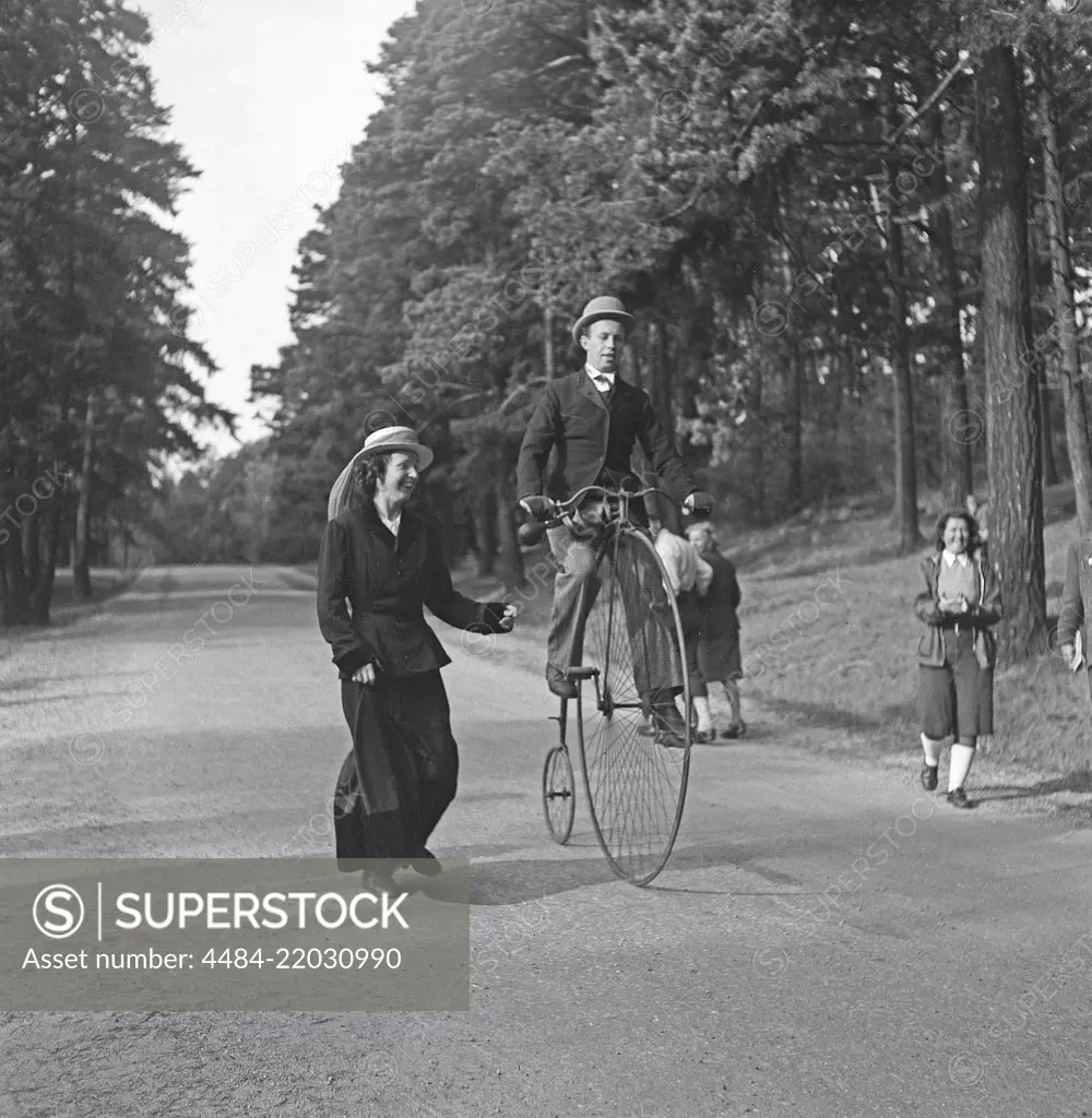 Penny farthing bicycle. A man is riding a penny farthing bicycle