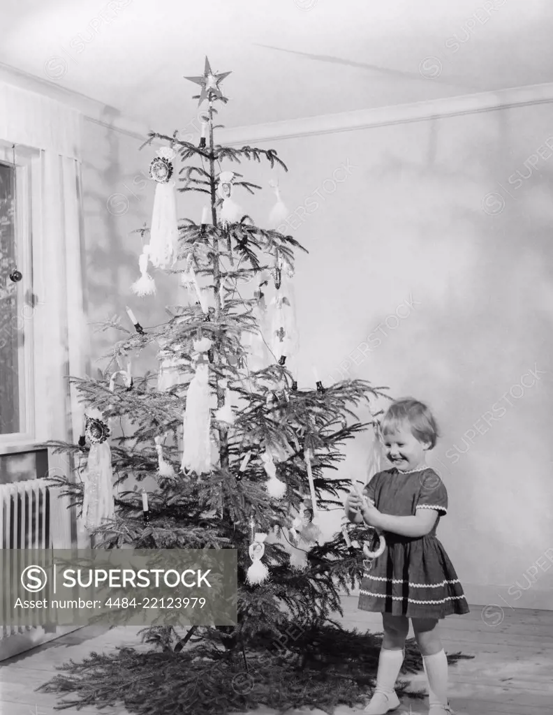 Christmas in the 1950s. A young girl is standing by the christmas tree. Sweden 1950s Ref 3113