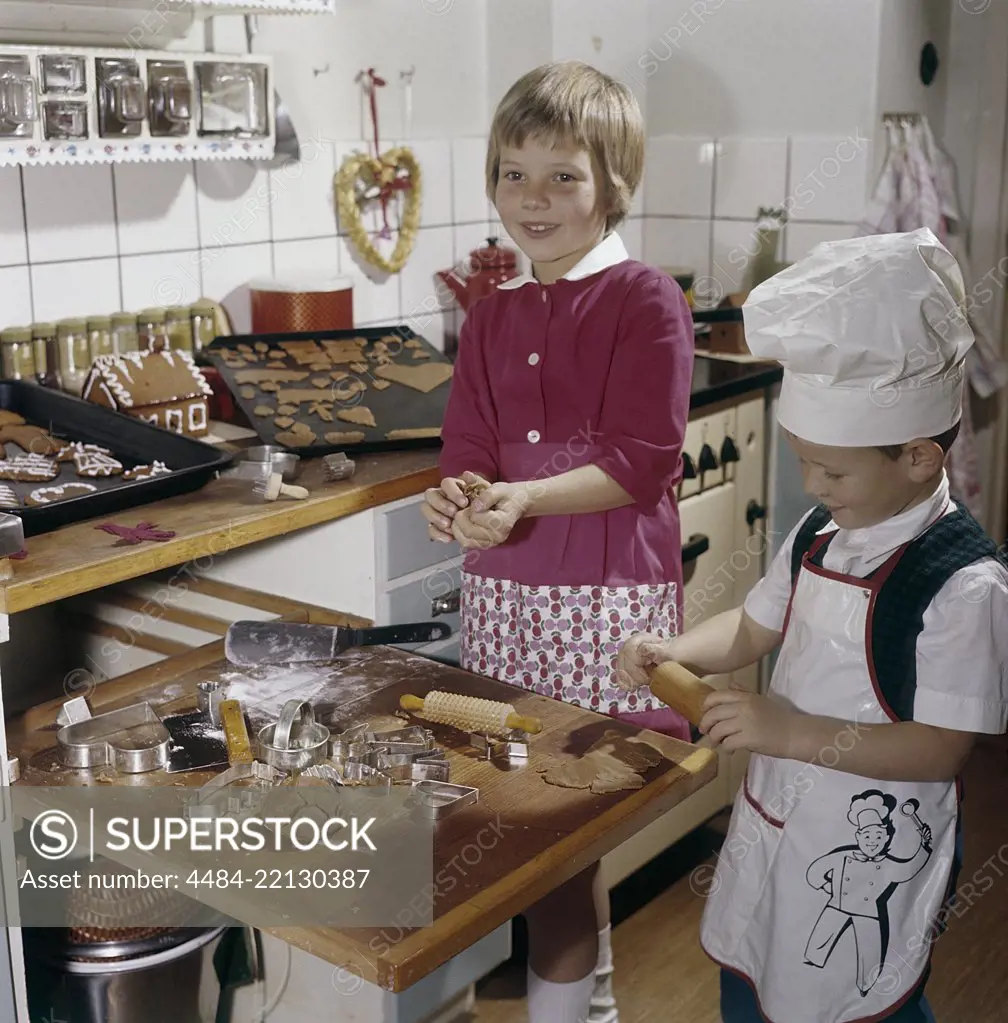 Christmas in the 1950s. A girl and a boy is busy in the kitchen baking ginger bread. With different shaped forms they get cakes as hearts and animals. Sweden 1950s. Ref BV86-10