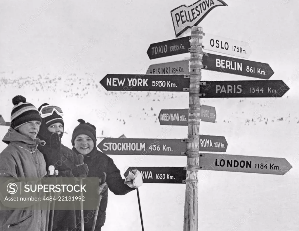 Winter in the 1960s. A group of young skiers is standing in front of signs where the distance to the cities like New York and London are listed in Km. Sweden 1967