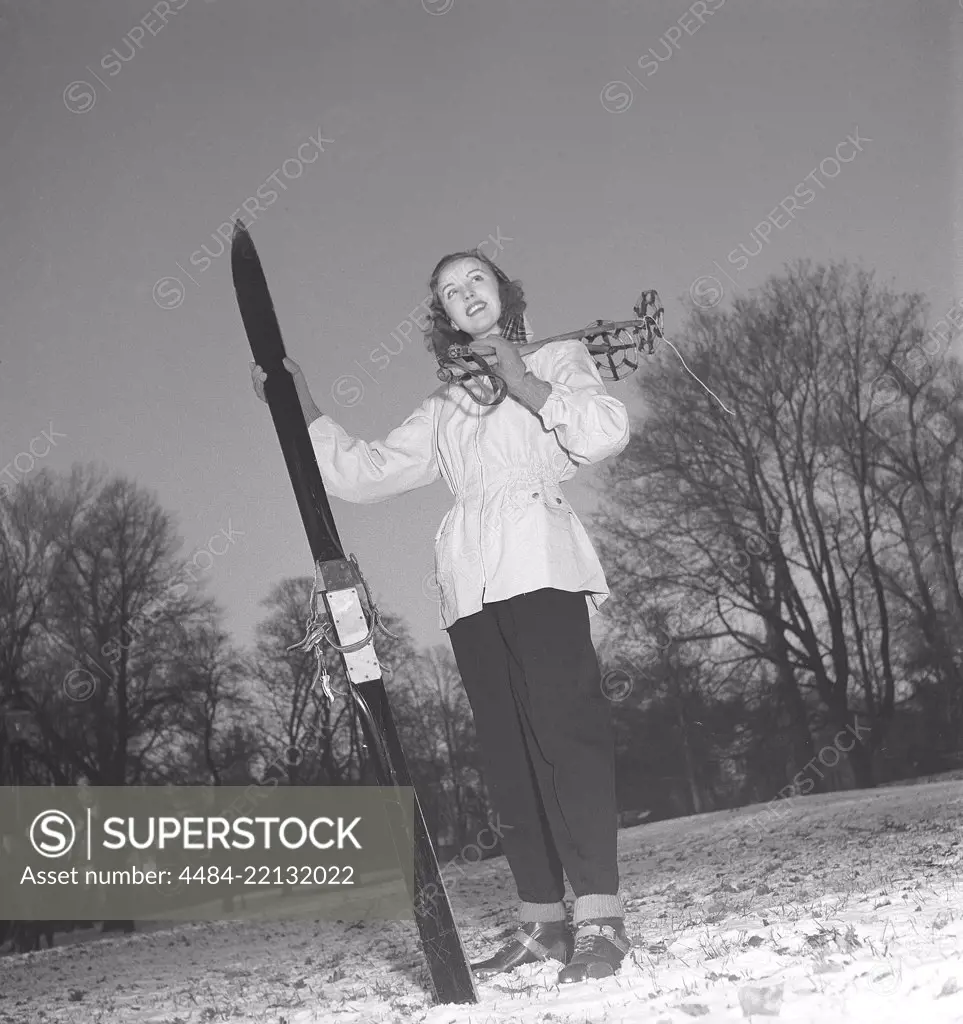 Winter in the 1940s. A young woman is wearing the typical 1940s winter sports clothes. Dressed in a practical wind jacket, ski pants and with a pair of skis and poles.  Sweden 1948. Photo Kristoffersson ref Y10-4