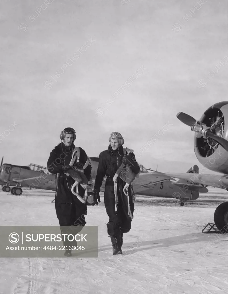 Pilots in the 1950s. Two pilots are walking past fighter aircraft a winter day. Sweden 1950s