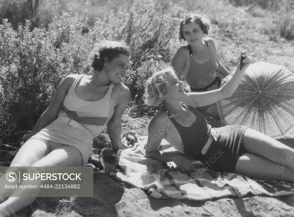 Having fun in the 1930s. Three young women on the beach dressed in