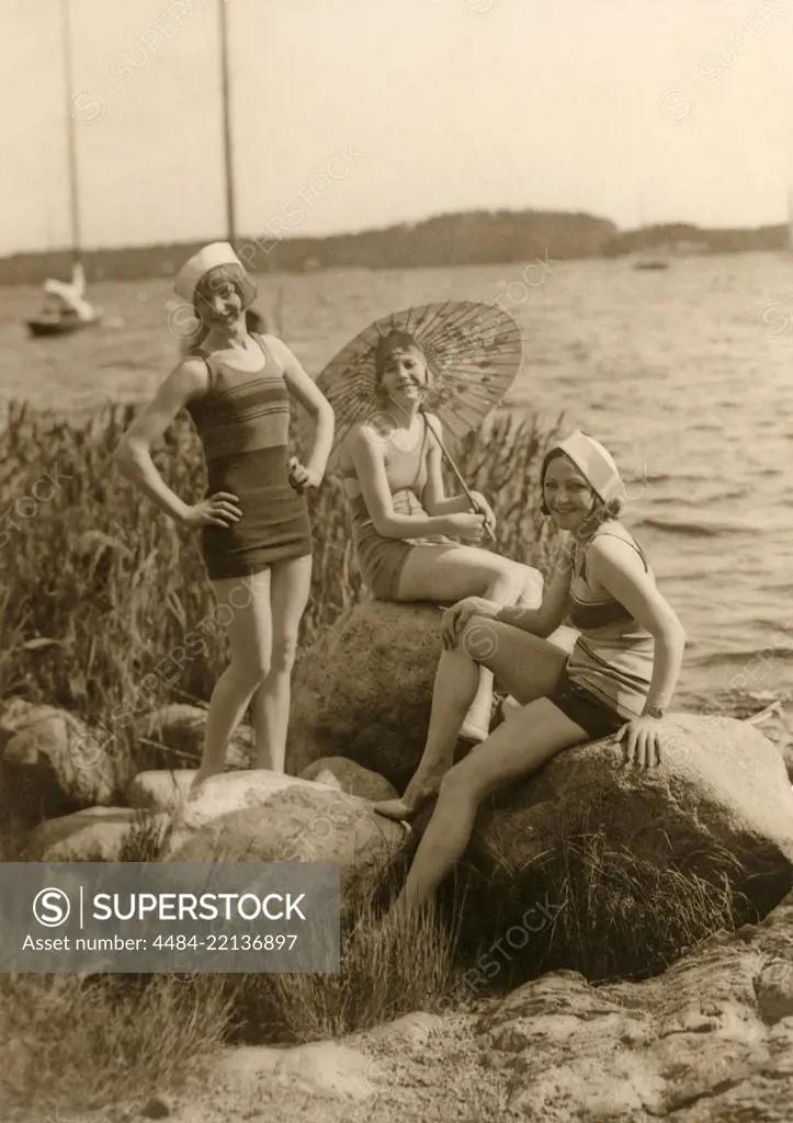 Having fun in the 1930s. Three young women on the beach dressed in the 1930s fashion of bathing suits. The fabric was cotton then. Sweden 1930s