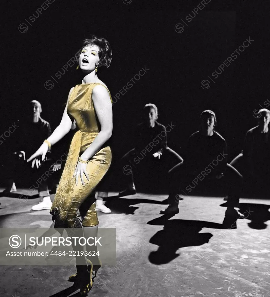 Singer in the 1960s. The young singer Lill-Babs performing and singing the hit song En tuff brud i lyxförpackning 1961. She is dressed in a tight golden dress. Photo Kristoffersson Ref CS27-1