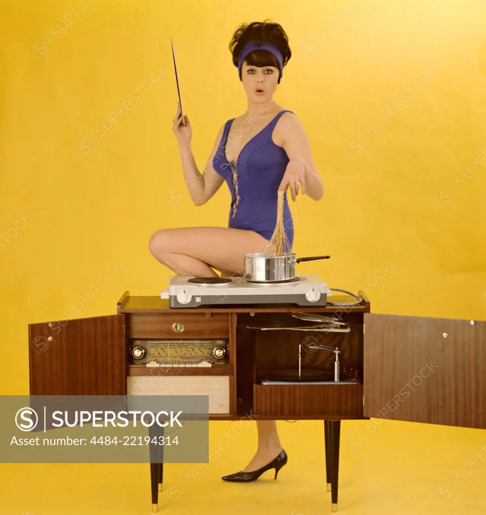 1960s bikini. A young brunette in a swimsuit. Pictured when cooking on top of a combined radio record player. Sweden 1960s. Pirkko Mannola