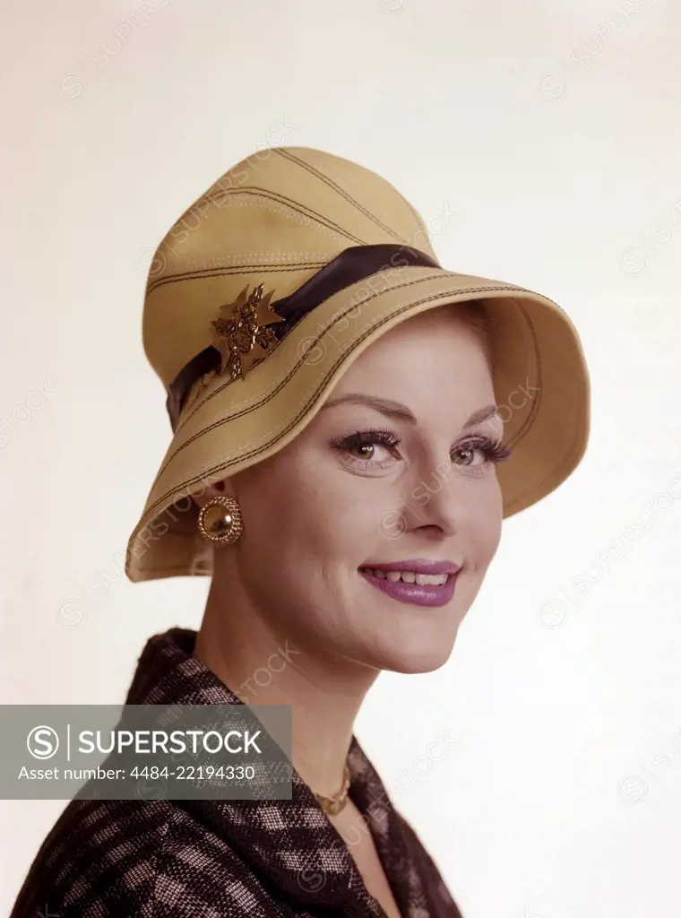 Woman of the 1960s. She is wearing a yellow summer hat. Matching golden necklace, earrings and brooch. Sweden 1960s