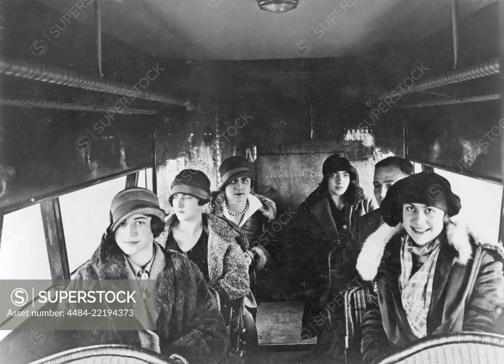 Airline travelling in the 1920s. A well dressed group of happy women, and a man, in a German Fokker passenger plane. They are all dressed in typical 1920s coats and hats. 1920s