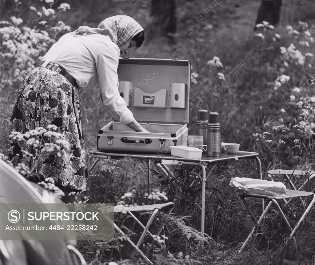 Camping in the 1960s. When camping in the 1960s plastic cups and other camping  equipment were sometimes packed and transported in special cases. Pictured  a practical such and a woman setting the