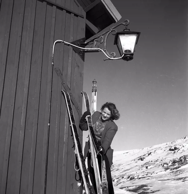 Winter in the 1940s. A young woman is preparing her skis and uses a seal skin underneath the skis to be able to climb the snowy mountain tops and not slide backwards. Sweden 1943. Kristoffersson Ref D70-4