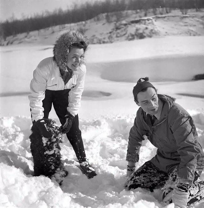 Winter in the 1940s. Actor Nils Kihlberg, 1915-1965 is pictured here with his wife Ann-Britt. They are both wearing winter clothes and plays in the snow laughing. Sweden 1943. Kristoffersson Ref D71-1