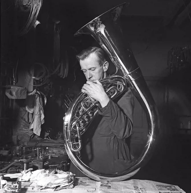 Workers in the 1940s. Interior of a mechanical workshop for musical instruments,  where a man is doing the last finishing touches to a tuba. Sweden 1941 Kristoffersson ref 225-1