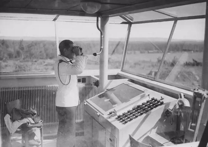 Air traffic controller in the 1940s. An officer in the airport control tower is monitoring the runway with binoculars.