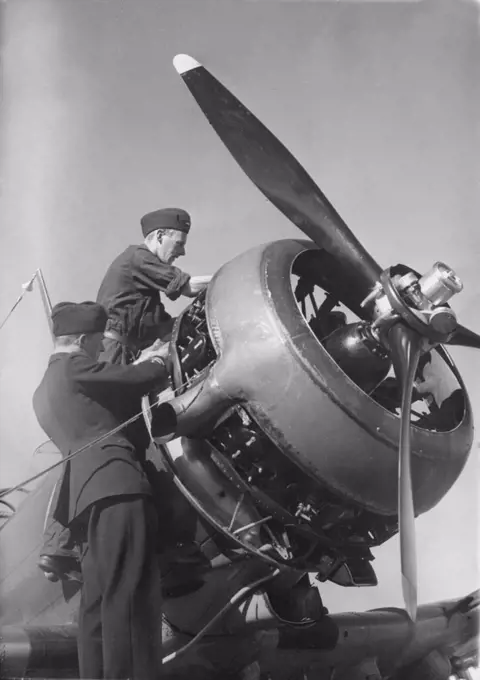 Airplane engineers.Three mechanics are performing the important last minute check of engine details before start. The airplane is a swedish single propeller engine light bomb and survaillance unit model B5. The swedish company Saab Svenska Aeroplan AB produced this airplane on license from American Northrop and their model 8A-1.  Picture taken in the 1940s during the second world war.