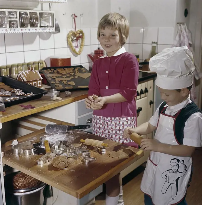 Christmas in the 1950s. A girl and a boy is busy in the kitchen baking ginger bread. With different shaped forms they get cakes as hearts and animals. Sweden 1950s. Ref BV86-10