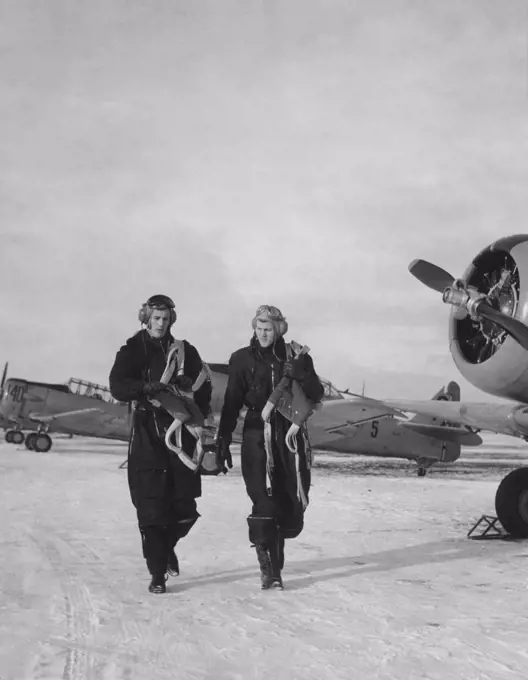 Pilots in the 1950s. Two pilots are walking past fighter aircraft a winter day. Sweden 1950s