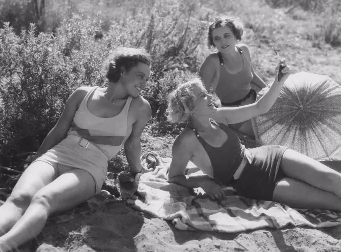 Having fun in the 1930s. Three young women on the beach dressed in the 1930s fashion of bathing suits. The fabric was cotton then. Sweden 1930s