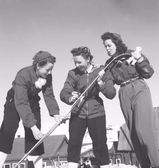 Winter in the 1940s. Three young women are going skiing and prepares the skis with ski wax to get better traction on the snow.  Sweden 1940s. Photo Kristoffersson ref D128-4