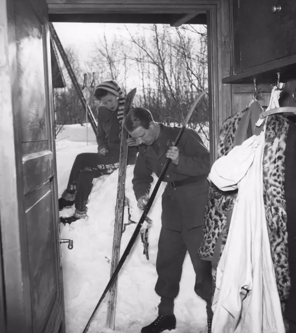 Winter in the 1940s. A young couple are going skiing and prepares the skis with ski wax to get better traction on the snow.  Sweden 1940s. Photo Kristoffersson 