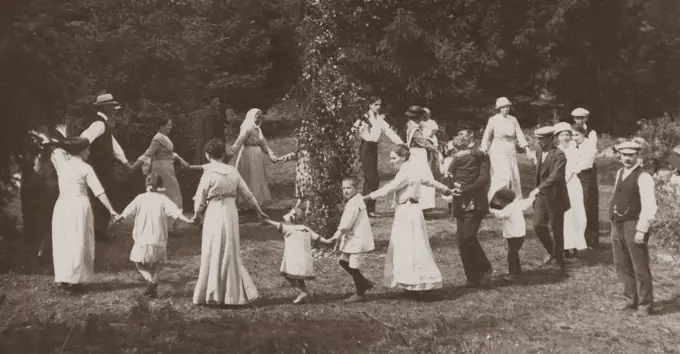 Midsummer tradition in Sweden. As a part of the festivities a Maypole is risen men, women and children gather to dance around it. Sweden at the beginning of the 20th century.