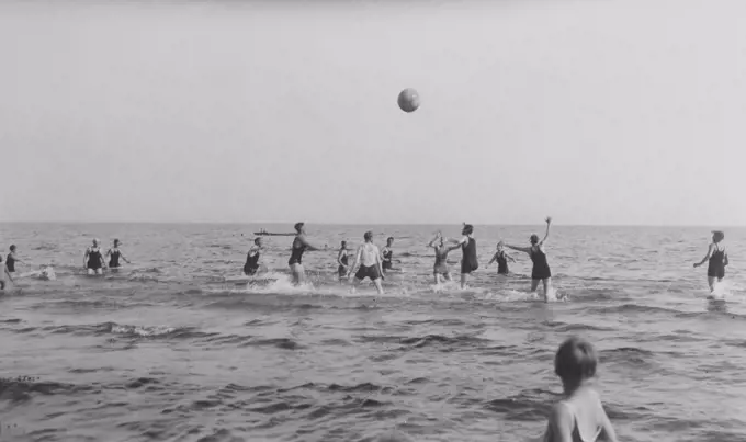 Summer in the 1920s. A group of people are playing ball in the water on a sunny day on the beach. Sweden 1920s