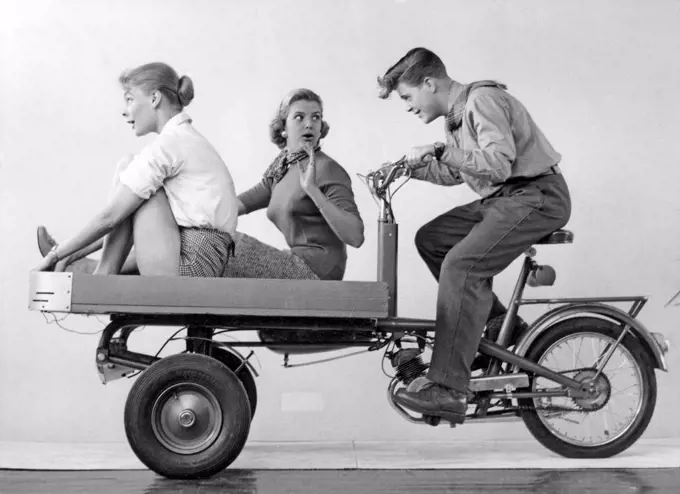 Teenagers of the 1950s. A teenage boy with two girls on the Monark transportation moped. Sweden 1950s.