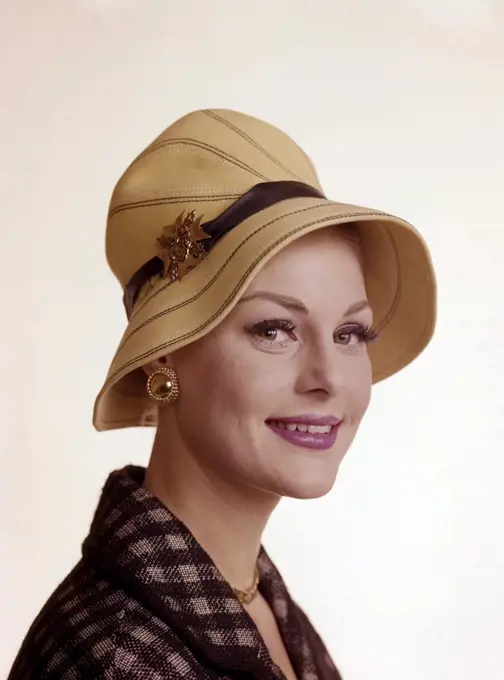 Woman of the 1960s. She is wearing a yellow summer hat. Matching golden necklace, earrings and brooch. Sweden 1960s