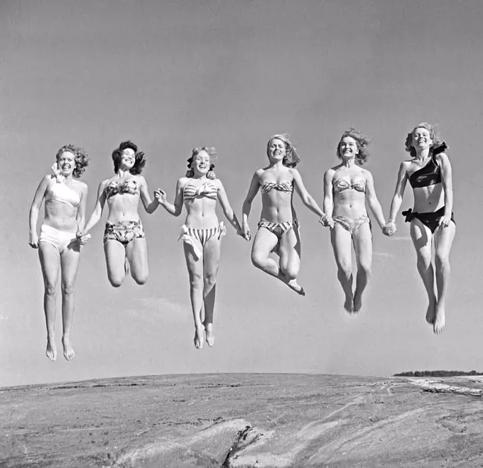 1940s summer. A group of young women in their bikinis are happy on this summer's day, jumping of joy. Sweden 1949. Photo Kristoffersson Ref AD24-5