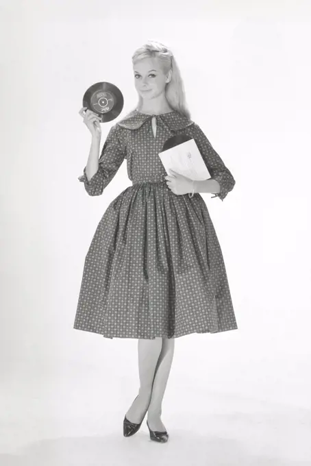 1950s fashion. A young woman in a typical 1950s dress. A wide skirt dress with a 50s patterened fabric. Sweden 1950s. Photo Kristoffersson ref CO93-4