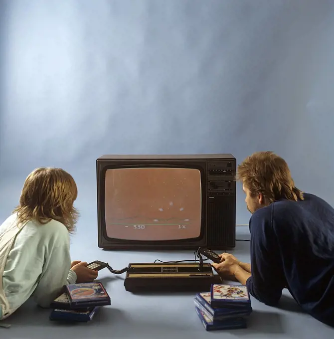 Home video games in the 1980s. A home video game console from Intellivison released by Mattel electronics in 1979. Pictured two people playing a game on a television set. ref BV97-5