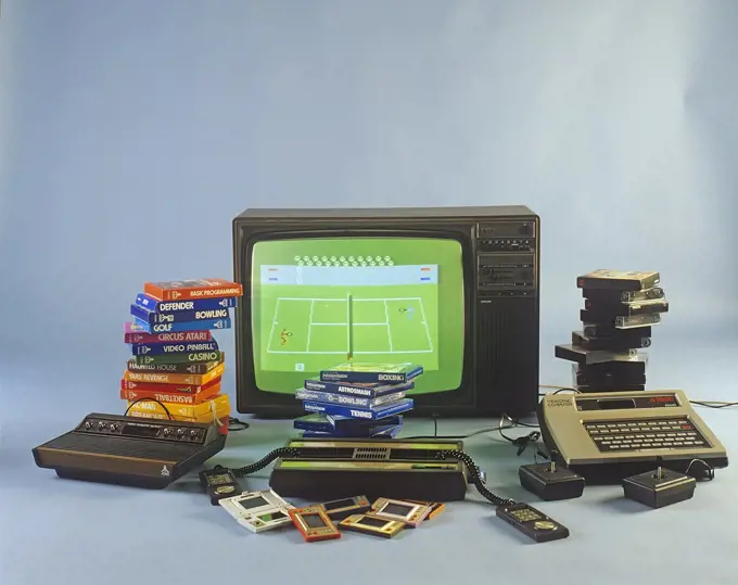 Home video games in the 1980s. A selection of the most popular game entertainment products in front of a television set. Atari, Intellivison, Philips Videopac G7000 and handheld consoles Game & Watch from Nintendo. 1980s. ref BV97-2